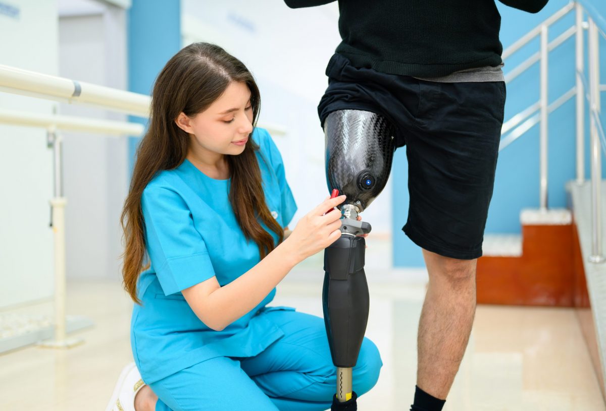 Physiotherapist adjusting prosthetic leg of patient in hospital