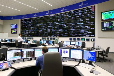 A large control room with several workers seated at 